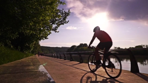 Unrecognizable Cyclist On Sunny Embankment