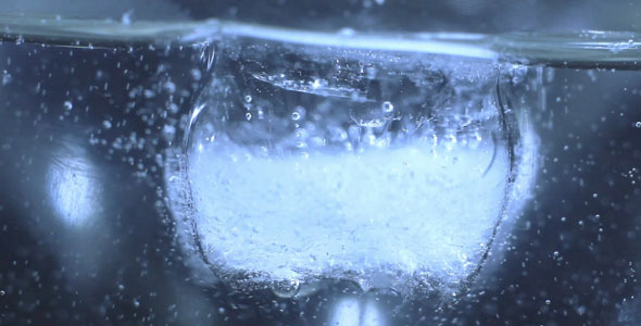Ice Cube Melting In Glass Of Water
