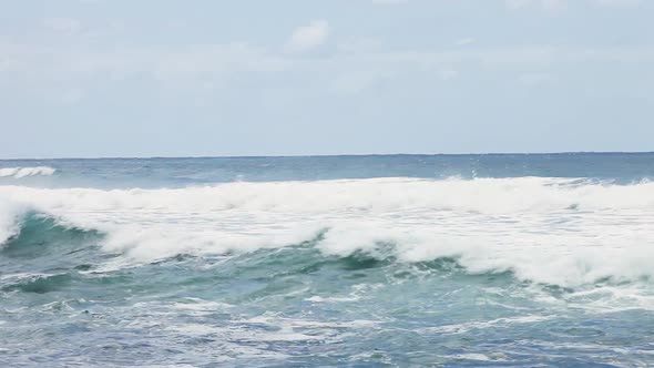 Rough tide waves on Australian coastline on slightly overcast day while the sun has a chance to shin