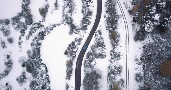Zenital drone shot of a Volskwagen California driving through the mountain roads of the Pyrinees.