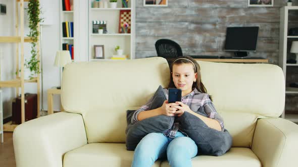 Cheerful Little Girl with Braces Sitting on the Couch