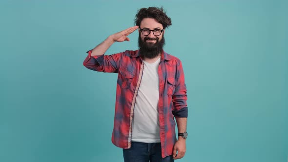 Happy Bearded Guy Saluting with Hand, Saying Yes Sir, on Turquoise Background