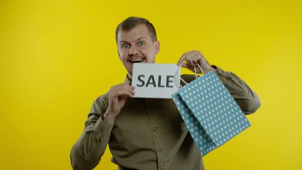 Man Showing Sale Word Inscription From Shopping Bag, Smiling, Rejoicing Discounts on Black Friday