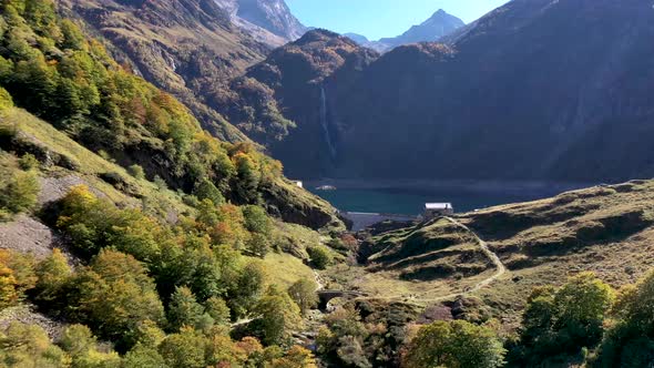 Lac d'Oô dam wall at the artificial lake in the French Pyrenees with view of the waterfall in the ba