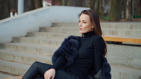 Sexy brunette woman posing wearing dark fur coat looking to tha camera with hands near face. Fashion