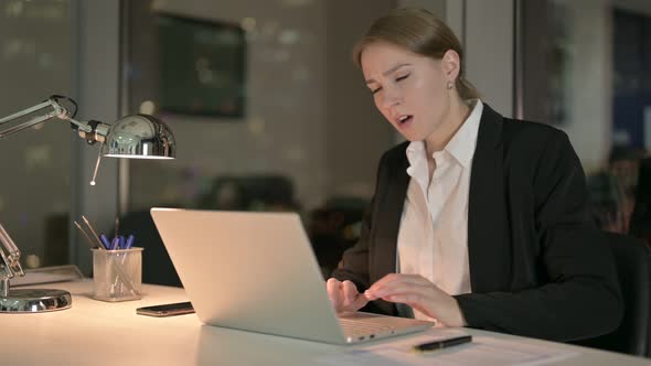 Tired Businesswoman Having Back Pain in Office at Night 