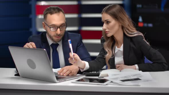 Male and Female Business Colleagues Discussing Work Pointing on Screen of Laptop at Hi Tech Office