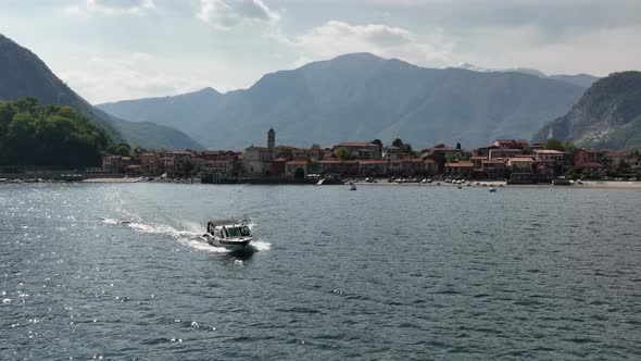 Low aerial shot of a boat pulling out of a marina of a mountain lake with a villa and towering mount