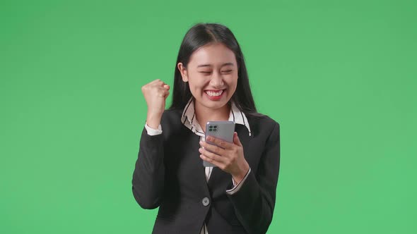 An Asian Business Woman Celebrating While Using Mobile Phone In The Green Screen Studio