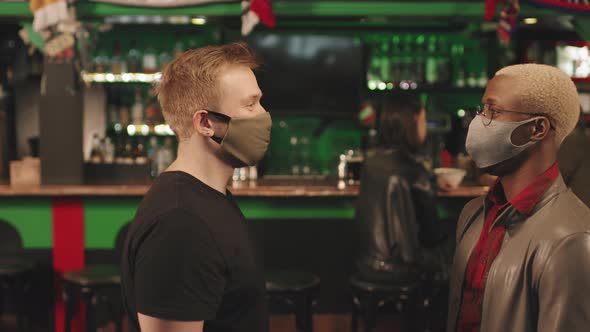 Men In Masks Greeting Each Other At Bar