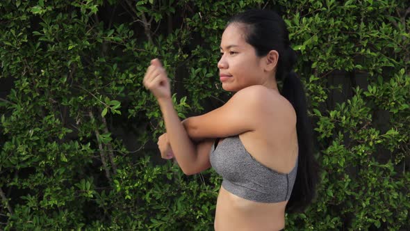 Thai Woman Woman Exercising Doing Cross Arm And Triceps Stretch. - medium shot