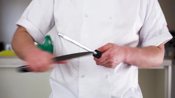 professional male chef sharpening a knife with a steel in his chef whites ready to cook a gourmet me