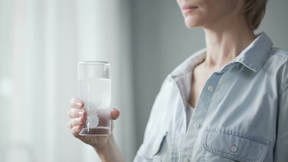 Female Putting Pill Into Glass with Water and Drinking It, Woman's Health