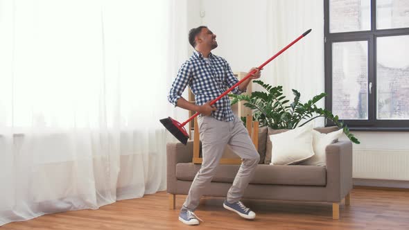 Man with Broom Cleaning and Having Fun at Home 