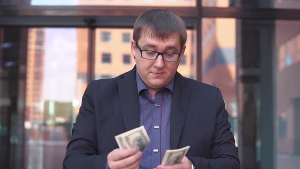 A Businessman Counts Money Standing Near the Business Center