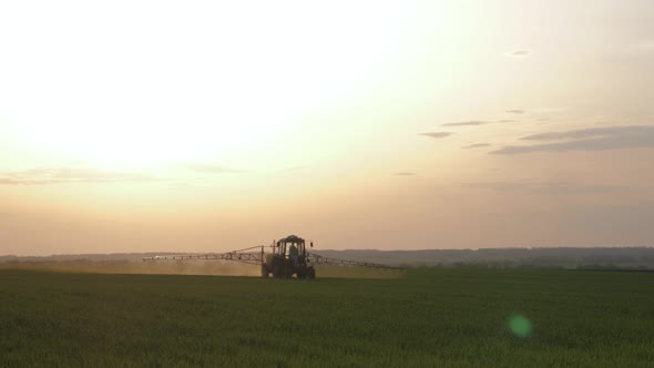 Farming Tractor Spraying on Field with Sprayer, Herbicides and Pesticides at Sunset. Farm Machinery