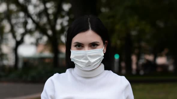 Portrait of Beautiful Young Woman Wearing Medical Face Mask Standing Outside Looking at Camera