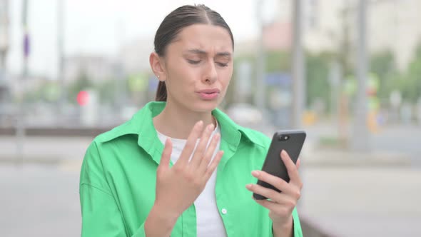 Upset Hispanic Woman Reacting to Loss on Smartphone Outdoor