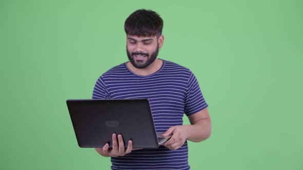 Happy Young Overweight Bearded Indian Man Video Calling with Laptop