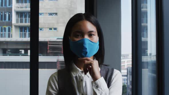 Portrait of asian woman wearing face mask standing in modern office