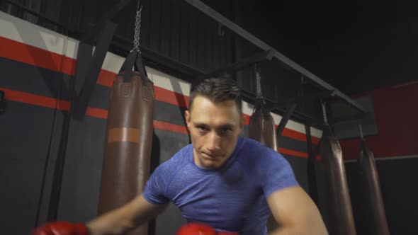 Strong caucasian man punching in front of camera, combat punches in boxing sport club workout