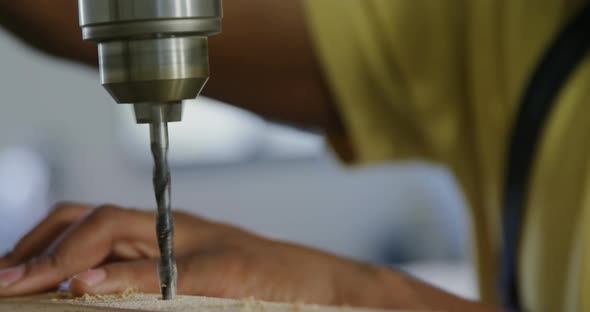 Carpenter drilling wooden plank with machine in workshop 4k