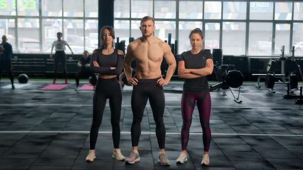 Portrait of group of young athletes looking at camera show thumbs up stand in a row in fitness gym