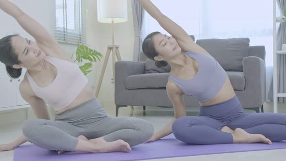 Asian people practicing yoga lifestyle class on a mat at living room