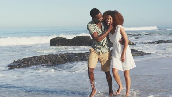 African American couple walking seaside and kissing