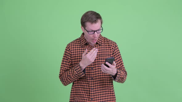 Young Handsome Hipster Man Using Phone and Looking Surprised