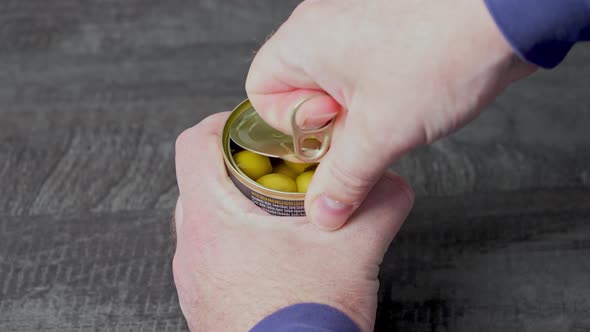 Man Hand Opens Jar with Green Olives