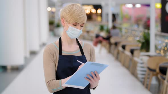 Closeup Caucasian Middleaged Woman Cafeteria Restaurant Worker Waitress in Medic Face Mask Writing