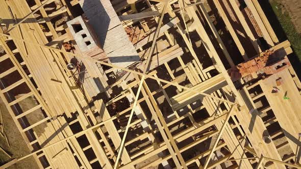 Aerial view of unfinished brick house with wooden roof frame structure under construction
