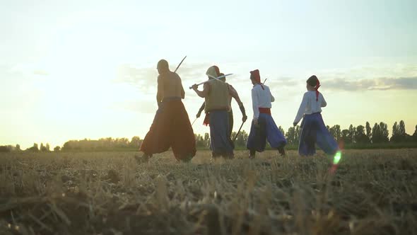 Group Cossack Men Traditional Clothes Swinging Spinning Sharp Shashkas Against Cloudy Sunset Sky