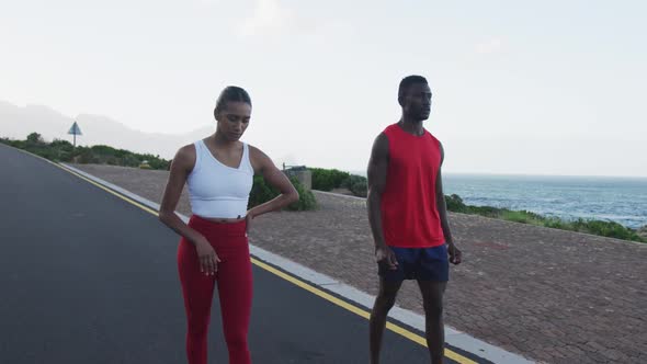 Diverse fit couple exercising running on a country road near mountains