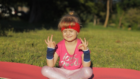Child Sitting on Mat and Performing Yoga Meditation Outdoors in Park, Girl Doing Yoga Exercises