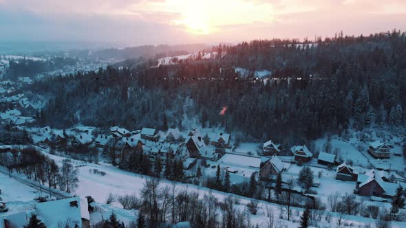 Aerial Footage Of Sunrise With Clouds In A Town With Snowy Roads and Forest