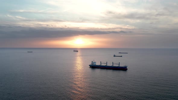 A drone flight around container ships into the sea at sunrise