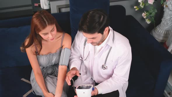 High view doctor explain blood pressure result to patient in reception area in front of laptop