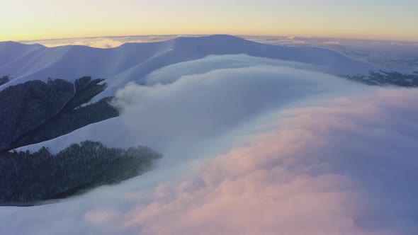 Cloud Waves Gently and Slowly Flow Over the Tops of Snowcapped Mountains Covered with Spruce Forests