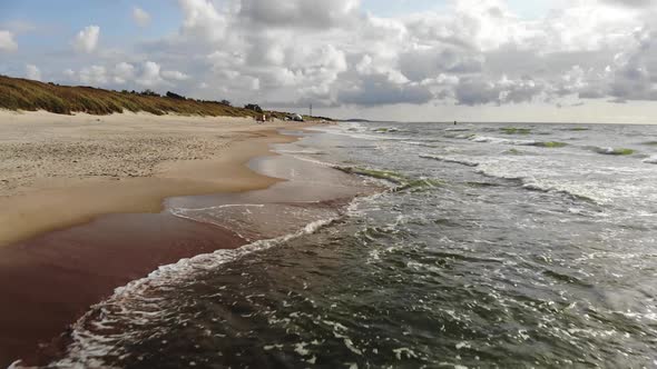 AERIAL: Flying very low over sandy beach while revealing crashing waves