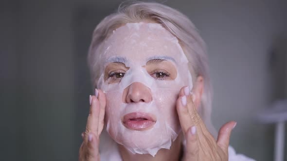 Headshot Confident Middle Aged Caucasian Woman Applying Face Mask in the Morning at Home Looking at
