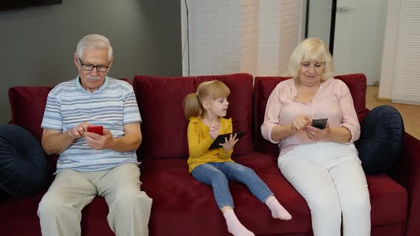 Senior Couple Grandparents with Child Girl Grandchildren Using Digital Tablet, Mobile Phone