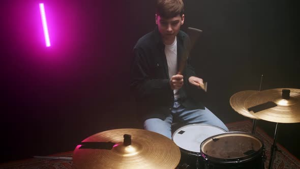 Drummer Playing the Drum Set in a Dark Room on a Black Background