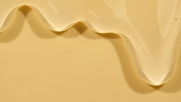 Beige Yellow Transparent Cosmetic Gel Fluid With Molecule Bubbles Flowing On The Plain Surface