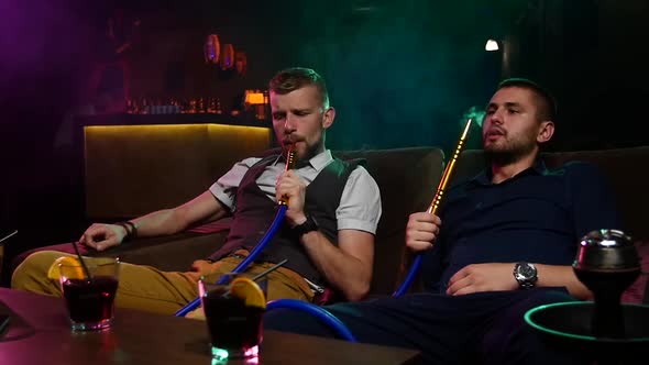 Two Young Men Smoke From Shisha Pipe. Slow Motion