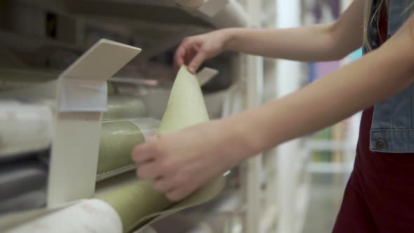 Woman is Feeling a Paper of Wallcovering in Showcase in a Store Closeup