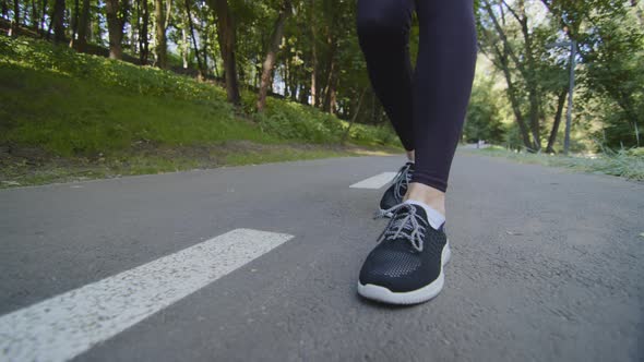 Unrecognizable Woman Sportswoman Runner Wears Black Clothes Runs in City Park in Nature on Summer