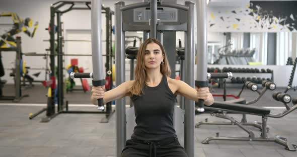 Young Woman Performs an Exercise in a Butterfly Simulator