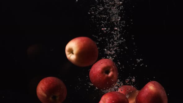 Red Apples Pouring To Water on Black Background, Fruits Falling Into Water, Slow Motion